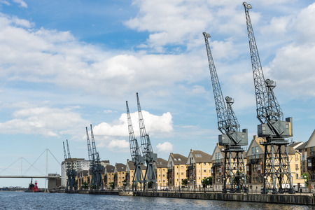 Old dockside cranes alongside a waterfront developmentのeditorial素材