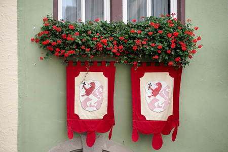 Red geraniums and flags on a house in Rothenburgの写真素材
