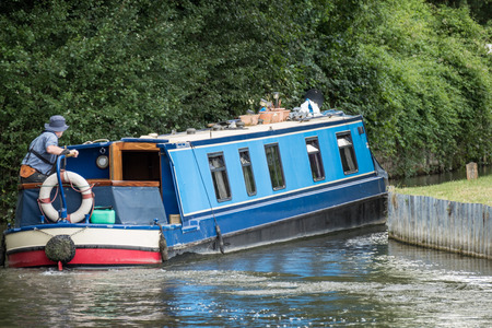 Narrow boat on the Kennet and Avon Canal near Aldermaston Berkshire on July 5, 2015. Unidentified manのeditorial素材