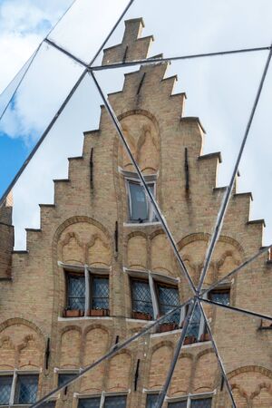 Split mirror of historic gabled buildings in Market Square Bruges West Flanders in Belgium