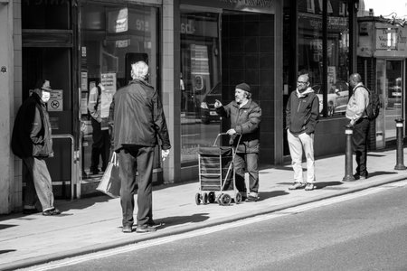 EAST GRINSTEAD, WEST SUSSEX, UK - APRIL 20 : Social distancing while queueing for the building society in East Grinstead due to Coronavirus on April 20, 2020. Unidentified peopleのeditorial素材