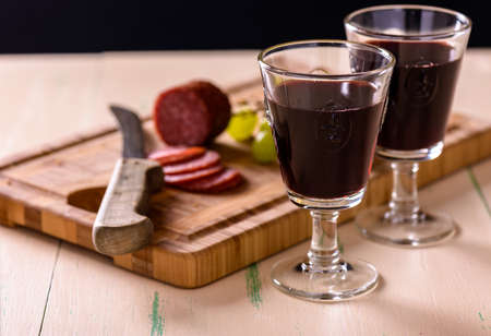 Red wine with salami and grapes on old wood table and some grapes on the sideの写真素材