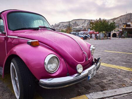 Goreme, Turkey - October 2019. Pink retro car on the paving square of Cappadocian town in the cloudy autumn morningのeditorial素材