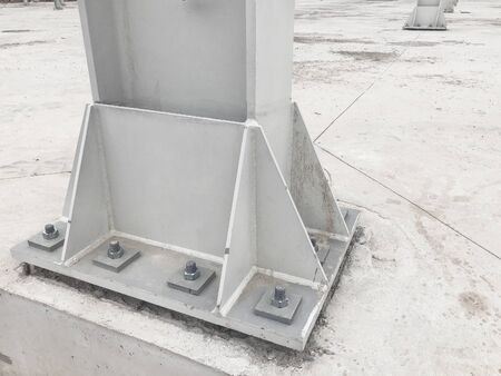 Metal pillar fastened to basement with anchor bolts and nuts. Supporting structures, metal frame of...