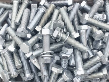 Steel bolts piled in the box. Fastening construction equipment. Fixing hardware.
