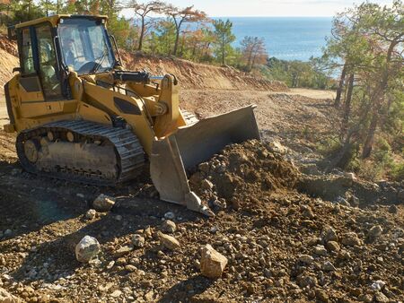 Bulldozer is moving soil during road construction works.