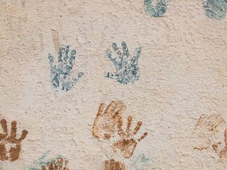 Blue and brown paint palm prints on the textured plaster.