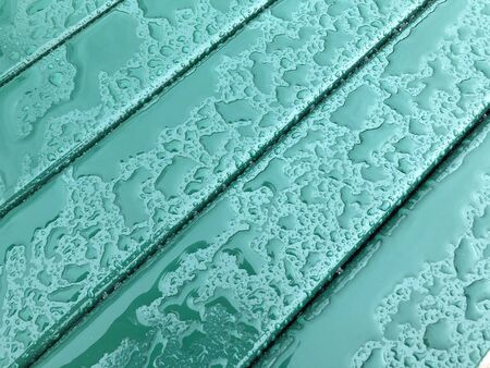 Rain drops on green colored metal surface.