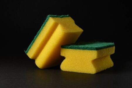 two new yellow sponges against black background.の写真素材