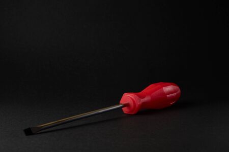 screwdriver with red handle on black background.の写真素材