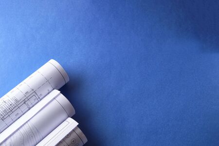 Rolled engineering drawings at blue background with copy space.の写真素材