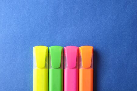 Multi colored highlighters at blue background with copy space.