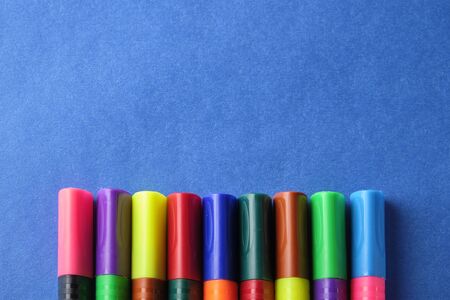 Multi colored felt pens with wrong color caps at blue background.