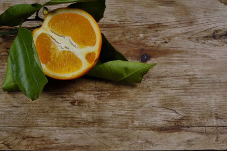 Orange with leaves on the weathered wooden surface copy space.の写真素材