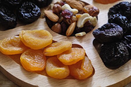 Dried apricots, prunes and nut mix at weathered wooden background.の写真素材