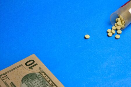 pills and dollars at blue background. healthcare insuranse concept, money for healthcare concept.の写真素材