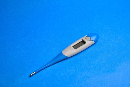 electronic thermometer at classic blue background with copy space.