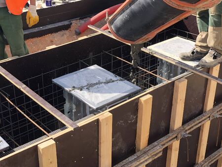 Construction workers are pouring concrete to formwork.