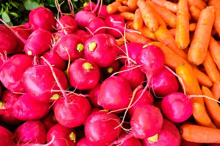 pink radish and orange carrots at market counter