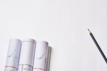 Rolled engineering drawings and pencil at blank white background with copy space.