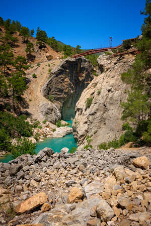 Metal pedestrian bridge over the gorge and mountain river. Yerkopru waterfall, Ermenek river, Mersin province,Turkeyの写真素材