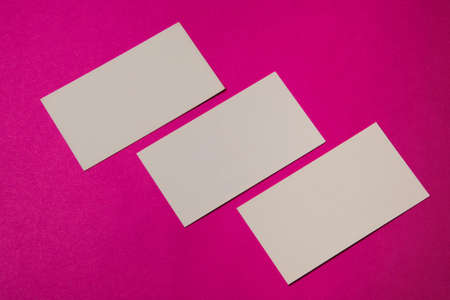 Blank business cards made of craft paper against magenta background.