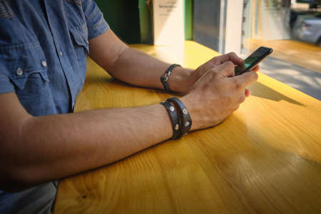 Hands of man holding phone and chatting online.