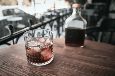 Crystal glass with ice and bottle with cold brewed coffee at table.の写真素材