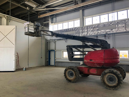 Manlifting vehicle inside industrial building. Man lifting platform machinery.