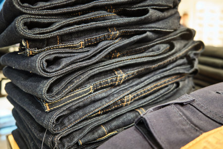 Stacks of denim pants hang on retail store shelf.の写真素材
