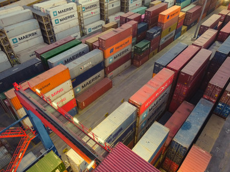 Stacked cargo containers and overhead gantry crane. Aerial view. Mersin, Turkey - December 2020.