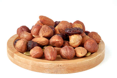 Hazelnut and almond kernels, raw pumpkin seeds and raisins on bamboo plate