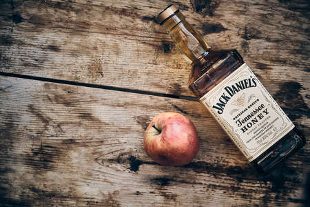 Jack Daniels Honey liqueur and apple fruit at weathered wooden backgroundのeditorial素材