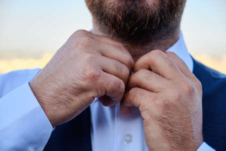 Man buttons his white shirt up