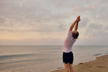 Man practices Surya Namaskar pose at sea beach