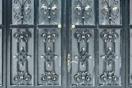 Black wrought iron doors with golden ornamentsの写真素材