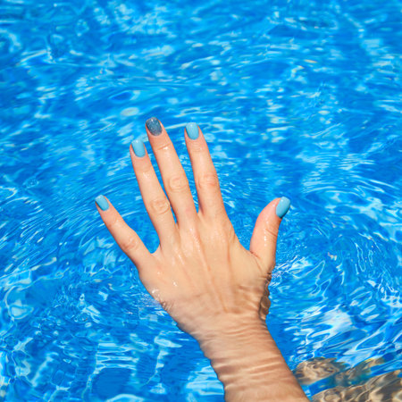 Hands with bright nail polish inside of waterの写真素材