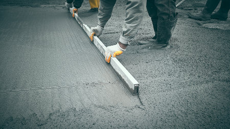 Cast-in-place work using trowels. Workers level cement mortar. Construction worker uses trowel to level cement mortar screed. Concrete works on construction siteの写真素材