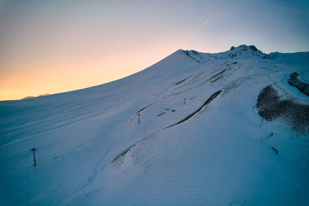 Sunset in winter mountains. Sun sets behind snow-covered slope. Erciyes mount, Kayseri, Turkiyeの写真素材