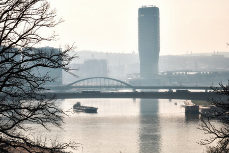 Cargo ship sailing on the Sava river under Brankov bridge opposite riverside of Belgrade and Belgrade Tower. Bulk carrier sails down the Sava river, Belgrade, Serbia. barge sailing down the riverの写真素材