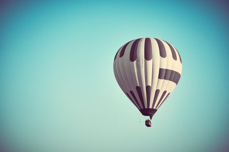 Flying hot air balloon against bright blue skyの写真素材