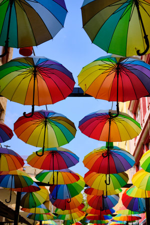 Lots of rainbow-colored umbrellas hanging above street. Decoration of streets made of umbrellasの写真素材