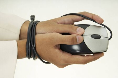 A woman holds a mouse and her hands are bound by the cableの写真素材