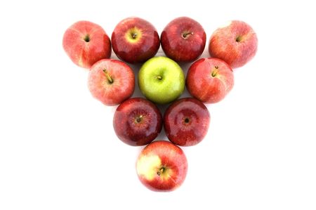 A green apple in a triangle of red applesの写真素材
