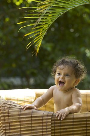 A toddler enjoys bath time in the tropical gardenの写真素材