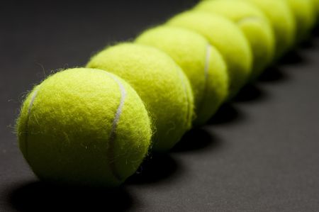 A macro shot of a line of tennis balls on a dark background. Shallow depth of field with focus on first ball.の写真素材