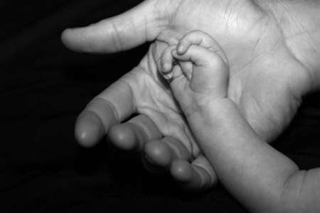 a newborn baby rests his hand in the palm of his Dad's