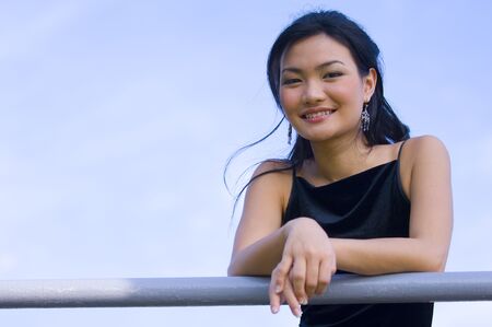 A beautiful young asian woman against a subtle blue skyの写真素材