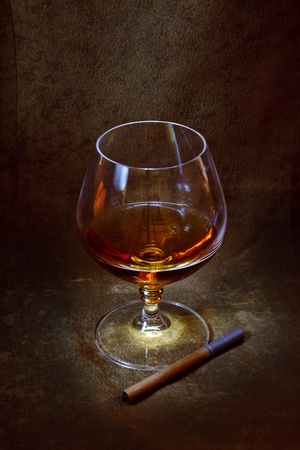a glass of brandy and a cigarette in the background of brown suedeの写真素材