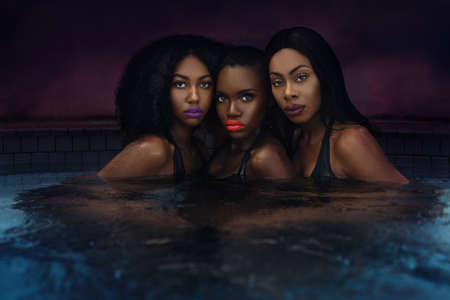 A portrait of three sensual young black females with black hair, beautiful makeup, popping lip...